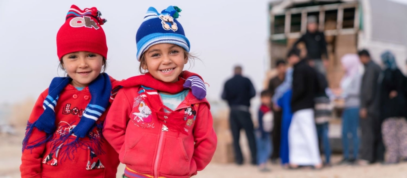 2 enfants syriens sourient à la caméra après avoir reçu des kits de vêtements d'hiver de l'UNICEF et de son partenaire Mateen.