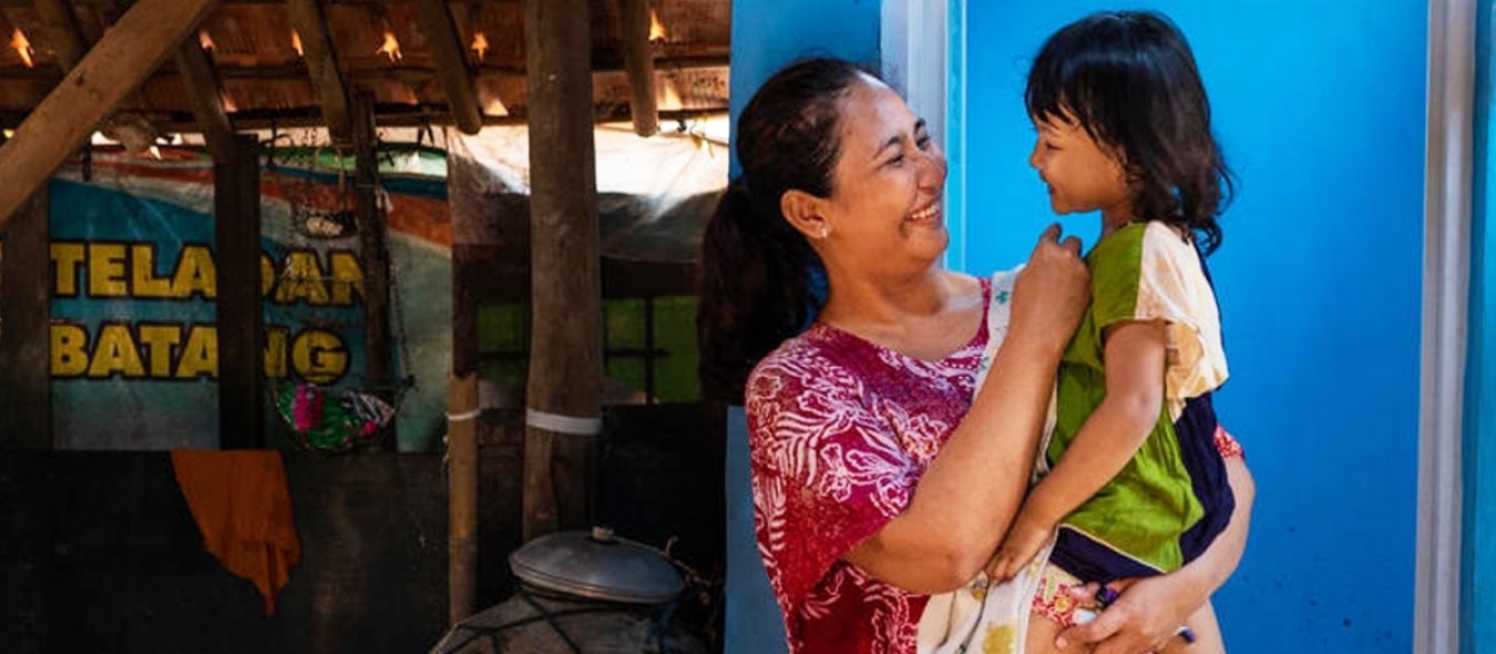 Une mère tient sa fille de 3 ans devant des toilettes nouvellement construites dans leur maison.