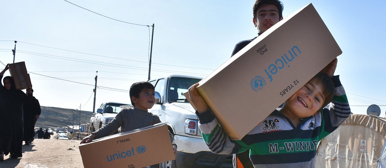 Boys holding UNICEF aid boxes.