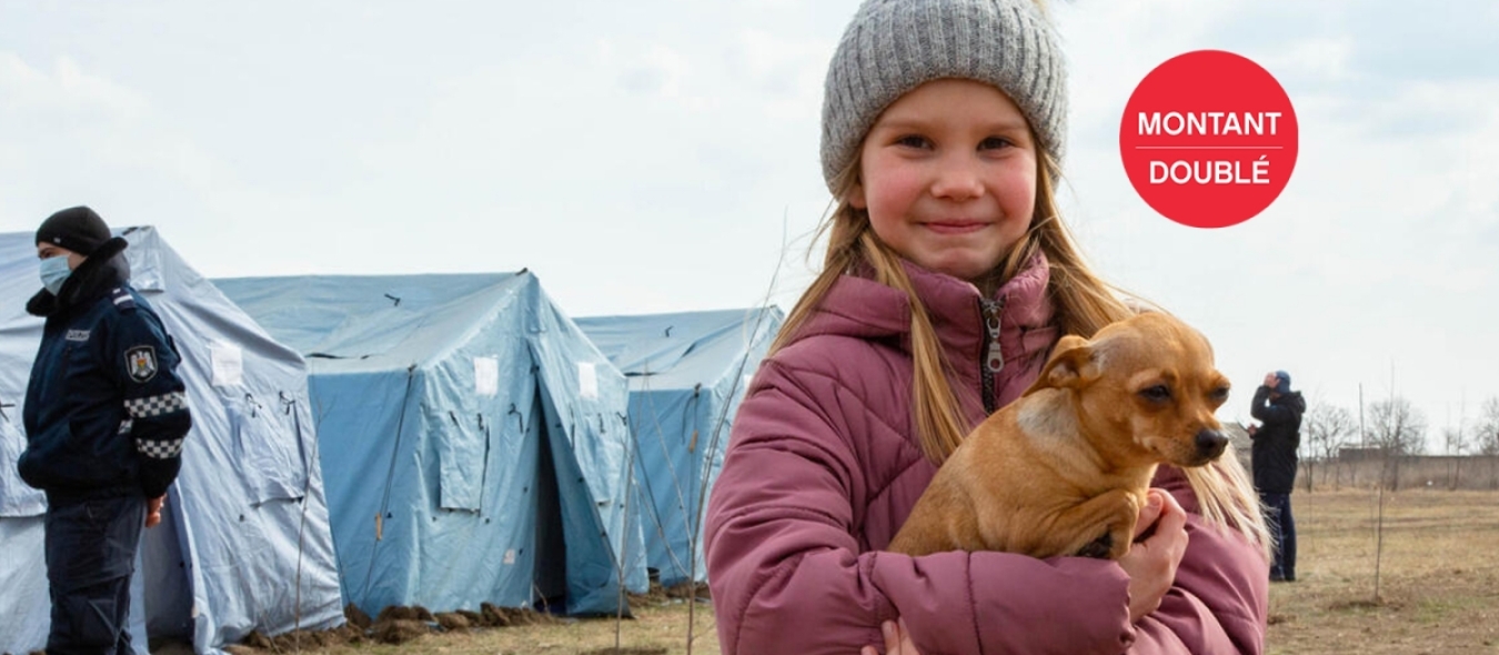 Une enfant réfugiée d'Ukraine se tient avec son chien dans un centre de réfugiés temporaires.