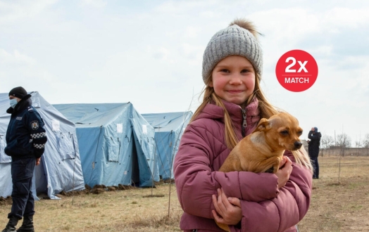 A refugee child from Ukraine stands with her dog at a Temporary Refugee Center.