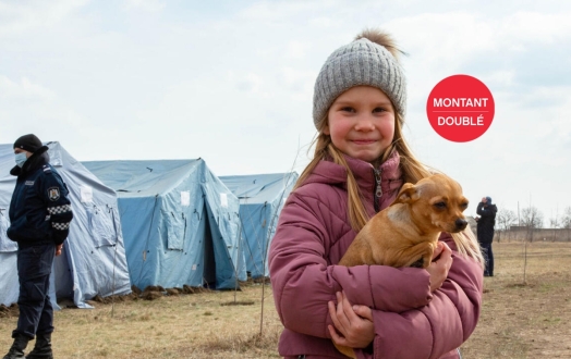 Une enfant réfugiée d'Ukraine se tient avec son chien dans un centre de réfugiés temporaires.