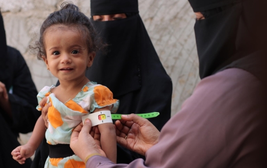 A child is screened for malnutrition using MUAC tape.
