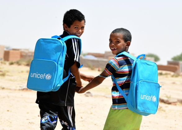 Two smiling boys wearing UNICEF backpacks.