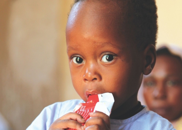 Un garçon mange un paquet de Plumpy'NutMD au centre thérapeutique ALIMA pour enfants souffrant de malnutrition, soutenu par l'UNICEF.