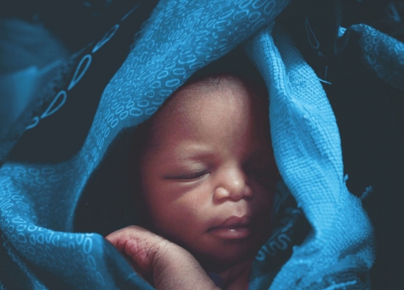 Close-up of a sleeping baby in blue baby blanket. 