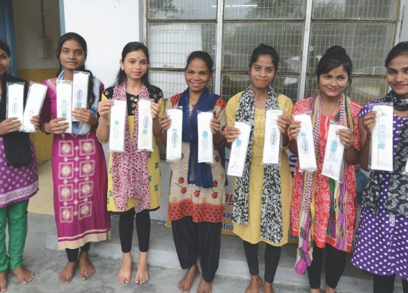 Girls hold packets of reusable sanitary napkins, which they received from UNICEF.