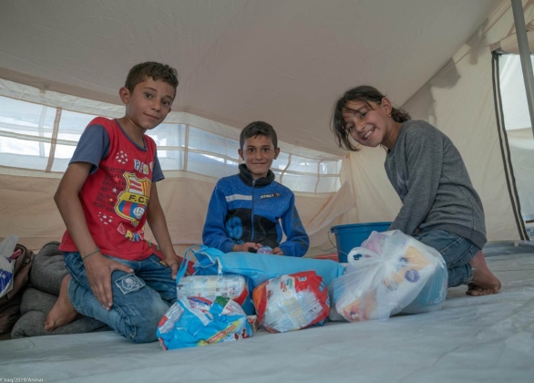 Three children open the Baby and Family Hygiene Kits provided by UNICEF inside their tent at the Barderash camp.