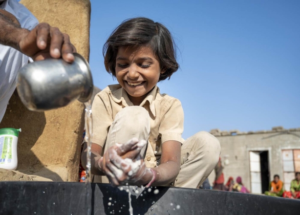 Un membre de la communauté aide son enfant à se laver les mains avec du savon en utilisant les bonnes méthodes de lavage, au Bangladesh.