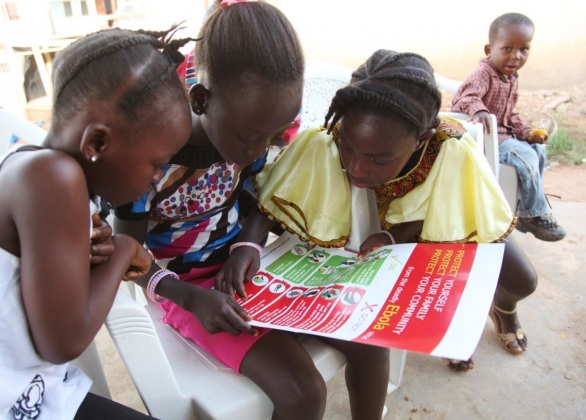 Des enfants lisent le dépliant se trouvant dans la trousse de protection contre l’Ebola pour les ménages.